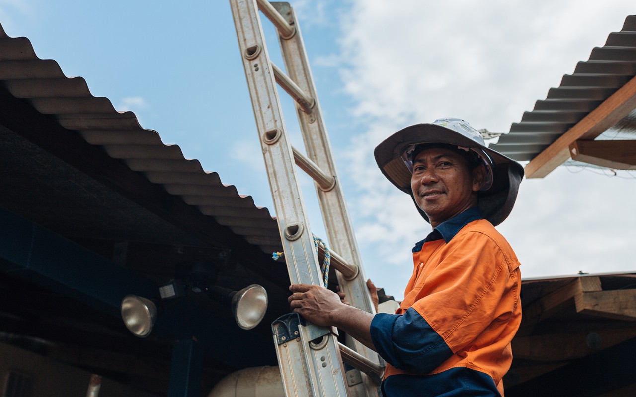 A tradie climbing a ladder